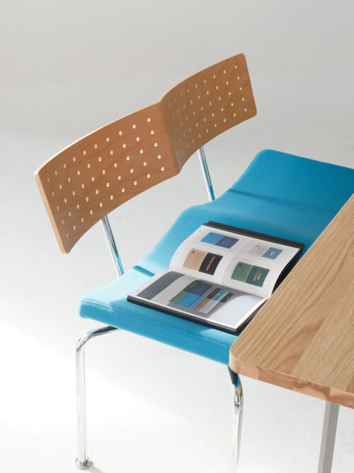Flying Bench with blue upholstered seat beside a wood table