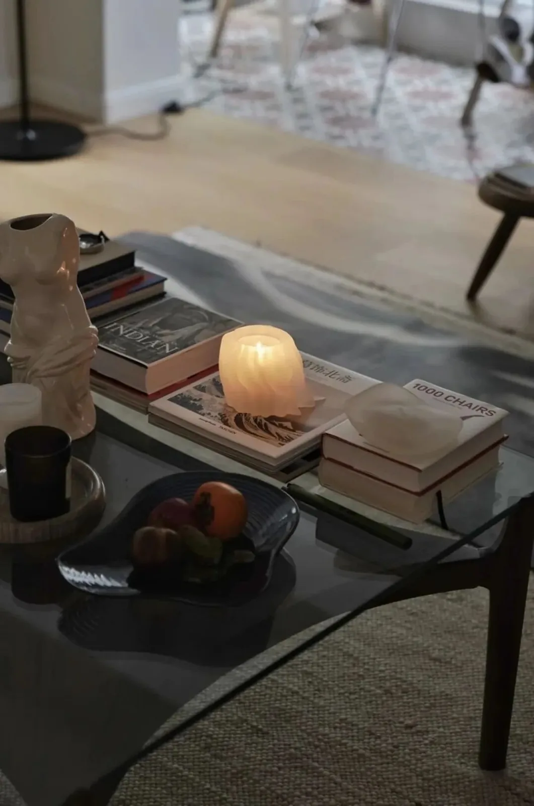 Furniture by the Window 19 Glass coffee table holding books in an evening living room