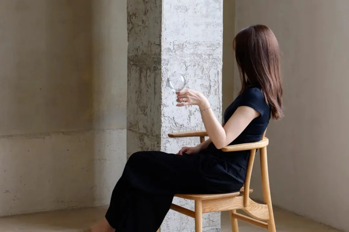 Natural wood Crown Chair shown in a concrete interior